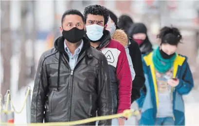  ?? GRAHAM HUGHES THE CANADIAN PRESS ?? People wear face masks as they wait to be tested for COVID-19 at a clinic in Montreal, Sunday. Quebec ushered in the new year by logging more than 7,600 new coronaviru­s cases over a three-day period.