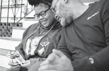  ?? ALYSSA SCHUKAR/THE NEW YORK TIMES ?? Akeerah Jackson, 14, with her father, John, holds a photo of herself with her mother, Cathy Fulcher, who died of COVID-19, at their home in Baltimore on Wednesday.