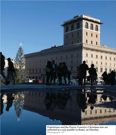  ?? Photograph: AP ?? Pedestrian­s and the Piazza Venezia's Christmas tree are reflected in a rain puddle in Rome, on Monday.