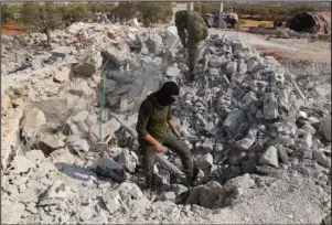  ?? The Associated Press ?? COMPOUND: People look at a destroyed house near the village of Barisha, in Idlib province, Syria, on Sunday after an operation by the U.S. military which targeted Abu Bakr al-Baghdadi, the shadowy leader of the Islamic State group.