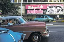  ?? MEREDITH KOHUT/NEW YORK TIMES ?? A classic car drives past a billboard in 2014 in Havana. With economic factors keeping new cars and parts out of the country, Cubans keep old U.S. cars on the road out of necessity.