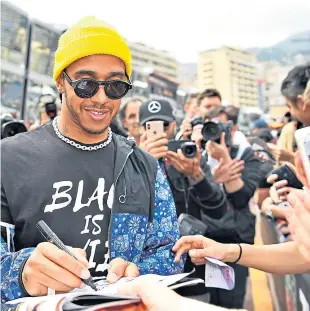  ?? Picture: PA. ?? Lewis Hamilton in the pit lane signing autographs in Monaco.
