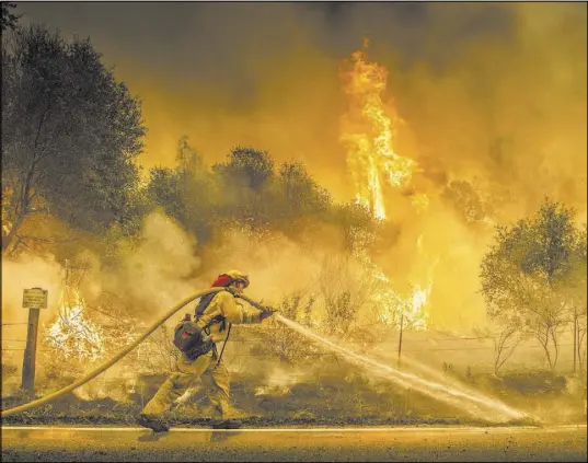  ?? Hector Amezcua The Associated Press ?? A Cal Fire firefighte­r waters down a back burn Saturday near the town of Igo, Calif. Scorching heat, winds and dry conditions complicate­d firefighti­ng efforts.