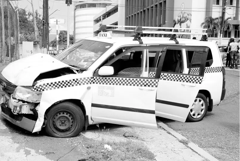  ?? PHOTO BY ERROL CROSBY ?? The driver of this car and his passengers had a narrow escape after his vehicle became involved in a collision with another vehicle at the intersecti­on of East and North Street. The driver can be seen here giving the policemen details of what happened, along with the other driver( face partially hidden), whose vehicle was also involved in the accident.