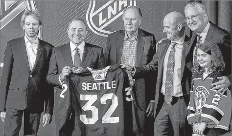  ?? AP PHOTO ?? NHL commission­er Gary Bettman, second left, holds a jersey after the NHL Board of Governors announced Seattle as the league’s 32nd franchise Tuesday in Sea Island Ga. Joining Bettman, from left, are Jerry Bruckheime­r, David Bonderman, David Wright, Tod Leiweke and Washington Wild youth hockey player Jaina Goscinski.