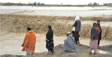  ?? ?? Wicked weather: people waiting to cross a flooded area in Spin Boldak district of Kandahar province, afghanista­n. — afp