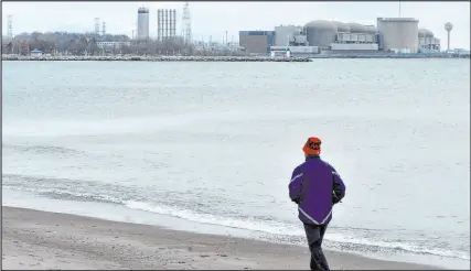  ?? Frank Gunn The Associated Press ?? A jogger runs along the beach past the Pickering Nuclear Generating Station in Ontario, Canada.