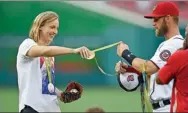  ?? NICK WASS / AP ?? Olympic champion swimmer Katie Ledecky hands her medals to Washington Nationals’ Bryce Harper to hold before throwing out the ceremonial first pitch as the Nationals hosted the Baltimore Orioles on Wednesday.
