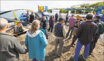  ?? Luis Sinco Los Angeles Times ?? VILLAGERS and dignitarie­s gather July 16 for a dedication ceremony for Igiugig’s new twin-turbine hydrokinet­ic generator, which unlike a convention­al hydroelect­ric system allows water, and salmon, to keep f lowing.