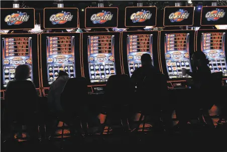 ?? Sue Ogrocki / Associated Press ?? Slot machine players gamble at a tribal casino in Thackervil­le, Okla. Gov. Kevin Stitt wants a bigger share of casino revenue.