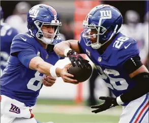  ?? John Minchillo / Associated Press ?? New York Giants quarterbac­k Daniel Jones hands off the ball to running back Saquon Barkley during the second quarter against the Houston Texans on Sunday in East Rutherford, N.J.