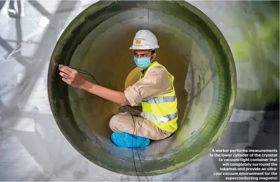  ??  ?? A worker performs measuremen­ts in the lower cylinder of the cryostat (a vacuum-tight container that will completely surround the tokamak and provide an ultracool vacuum environmen­t for the supercondu­cting magnets)