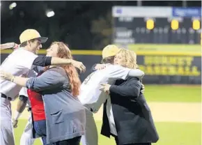  ?? JOE BURBANK/STAFF PHOTOGRAPH­ER ?? Molly and Judy Skinner, the sister and mother of Joe Skinner, a Bishop Moore Catholic High School baseball player who died of leukemia, get hugs from Bishop Moore players during a field dedication.