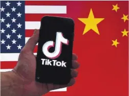  ?? Olivier Douliery / AFP ?? Móvil con el logo de TikTok delante de las banderas de China y EEUU.