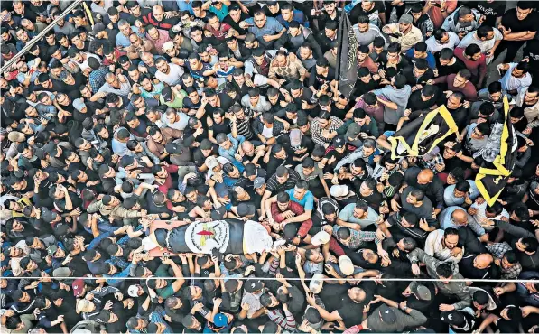  ??  ?? Crowds carry Baha Abu al-ata’s body at his funeral in Gaza City after the Islamic Jihad leader, far left, was killed in an Israeli airstrike on the city. Left, a rocket is fired from Gaza in the direction of Israel