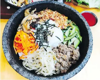  ??  ?? Dolsat bibimbap is served in a hot stone bowl and comes with seven different toppings, including marinated beef.