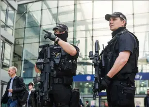  ?? Bloomberg photo by Matthew Lloyd ?? An armed police officer gestures to his colleague as they stand at Manchester Piccadilly railway station in Manchester, England, on May 23, 2017.