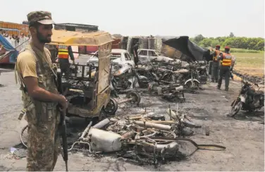  ?? SS Mirza / AFP / Getty Images ?? Soldiers guard the scene where a fuel truck crashed and exploded outside Bahawalpur, Pakistan.