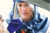  ?? AP PHOTO/ RICK BOWMER ?? Salt Lake County Health Department public health nurse Lee Cherie Booth performs a coronaviru­s test outside the Salt Lake County Health Department on Friday.