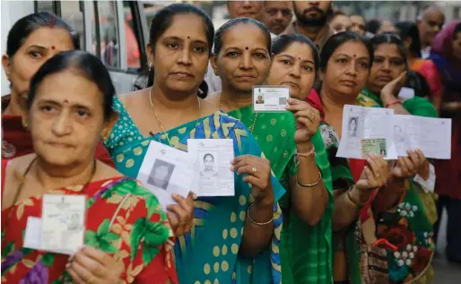  ?? AP ?? Women display their identity cards as they wait to cast their vote during the first phase of the Gujarat state assembly election in Rajkot on Saturday. —