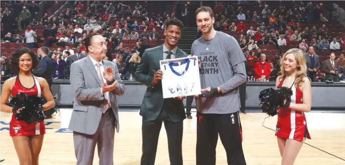  ?? | GARY DINEEN/GETTY IMAGES ?? Jimmy Butler passes his All-Star jersey to teammate Pau Gasol before the Bulls’ gameWednes­day against the Hawks. Gasol replaced an injured Butler as a reserve for the Eastern Conference.