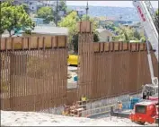  ?? John Gibbins San Diego Union-Tribune ?? A CONSTRUCTI­ON crew places the last panel of fencing in the 14-mile border wall replacemen­t project just east of the San Ysidro Port of Entry on Friday.