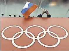  ?? DAVID J. PHILLIP, AP ?? Russian skating fan holds the country’s national flag over the Olympic rings during the 2014 Winter Olympics in Sochi.