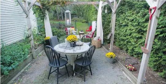  ?? GRAHAM HUGHES ?? The eating area in the backyard belonging to Mark LeGassick and Colleen Jorgensen is decorated with yellow flowers and white candles.