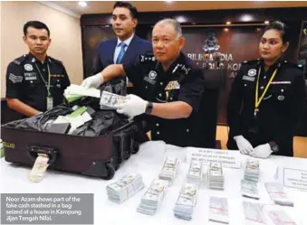  ??  ?? Noor Azam shows part of the fake cash stashed in a bag seized at a house in Kampung Jijan Tengah Nilai.