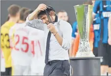  ?? — AFP photo ?? Inter Milan coach Antonio Conte takes off his medal as he walks past the trophy.