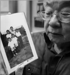  ?? AP PHOTO/RICH PEDRONCELL­I ?? In this photo taken on Tuesday, Les Ouchida holds a 1943 photo of himself (front row, center) and his siblings taken at the internment camp his family was moved to, as he poses at the permanent exhibit titled “UpRooted Japanese Americans in World War II” at the California Museum in Sacramento.