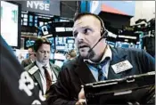  ?? RICHARD DREW/AP ?? Trader Michael Milano, right, works on the floor of the New York Stock Exchange. Equities shed 4% of value in a week.