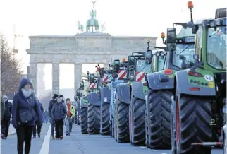  ?? /Sean Gallup/Getty Images ?? Taking a stand: Tractors of protesting farmers line the road in front of the Brandenbur­g Gate. The blockade coincides with a strike called by the train drivers union GDL this week.