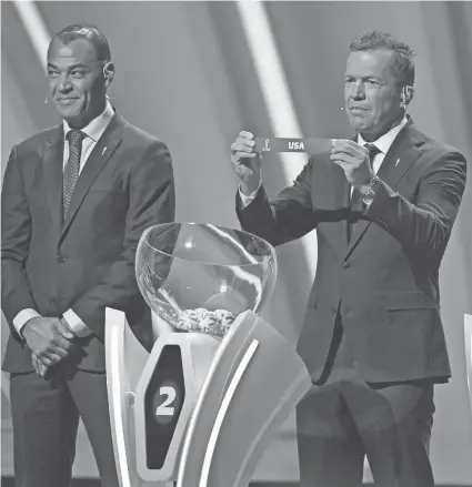  ?? DARKO BANDIC/AP ?? Former Brazilian soccer star Cafu, left, looks on as Lothar Matthaus holds up the name of the United States during the World Cup draw on Friday.