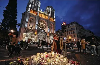  ?? Valery Hache / Getty Images ?? People light candles outside the Notre Dame Basilica in Nice a day after a knife attacker killed three people, cutting the throats of two, inside the church. Police have arrested a young Tunisian migrant who recently arrived in Europe.