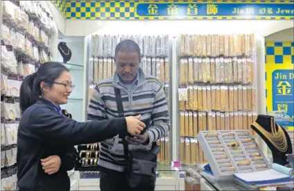  ??  ?? Bargains galore: A customer at a jewellery store in Xijiao market, Guangzhou, China, where traders buy cheap jewellery and (below) the pink plastic earrings that are popular in Ghana. Photo: Heidi Haugen