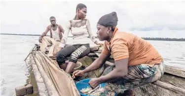  ??  ?? Debra Emiko, right, and her 18-year-old daughter, Mala Elizabeth, check their nets for fish April 24 near Warri, Nigeria.