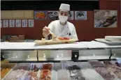  ?? EUGENE HOSHIKO / AP FILE ?? A sushi chef prepares a plate at the Toyosu Market in Tokyo. Japan has slipped to the world’s fourth-largest economy as government data released Thursday showed it fell behind the size of Germany’s in 2023.