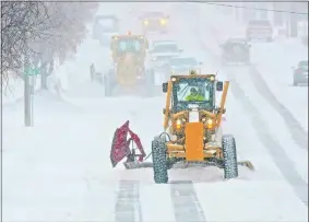  ?? TOM STROMME/THE BISMARCK TRIBUNE VIA AP ?? Motor graders plow Rosser Avenue as snow falls Friday in Bismarck, N.D.