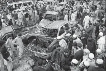  ?? MOHAMMED SAJJAD / ASSOCIATED PRESS ?? People view damaged vehicles after a blast Monday in Pakistan’s tribal area of Khyber.