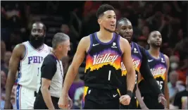  ?? RICK SCUTERI — THE ASSOCIATED PRESS ?? Phoenix Suns guard Devin Booker (1) reacts to the Philadelph­ia 76ers bench during the first half of an NBA basketball game, Sunday in Phoenix.