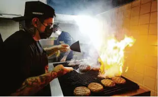  ?? Rubens Cavallari/folhapress ?? Cozinheiro prepara hambúrguer em dark kitchen de Santo André (ABC); parceria entre cervejaria e rede de lanches foi inaugurada recentemen­te