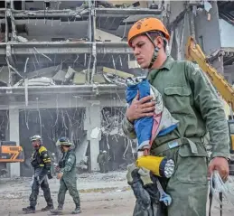  ?? (AFP) ?? A rescue worker carries a Cuban flag rescued from the debris of the Saratoga Hotel, in Havana, on Sunday