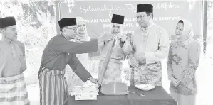  ??  ?? ASFIA bersama Dr Abdul Rahman Junaidi membuka lemang sebagai simbolik perasmian Majlis Ramah-Tamah Aidilfitri Kampung Bintawa Batu di Kuching, baru-baru ini.