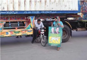  ??  ?? This picture taken on Friday shows a motorcycli­st slipping through a gap in a barricade set up using shipping containers, near Lahore airport, to block supporters of Pakistan Muslim League – Nawaz.