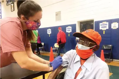  ?? The Associated Press ?? Q Debbie Monahan, a school nurse, pulls down Charles Robbins’ sleeve after giving him his second shot of a vaccine to protect against the coronaviru­s at Surry County High School in Dendron, Va., on Saturday. Getting the coronaviru­s vaccine has been a challenge for rural counties in the U.S. that lack medical facilities such as a pharmacy or a well-equipped doctor’s office.