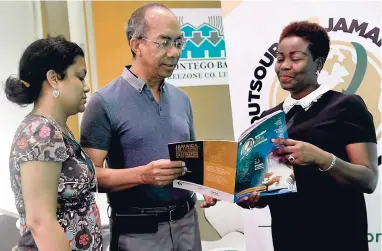  ??  ?? Dr Horace Chang, minister of national security, and his daughter, Melissa (left), peruse a copy of the O2J magazine with BPIAJ head Gloria Henry.