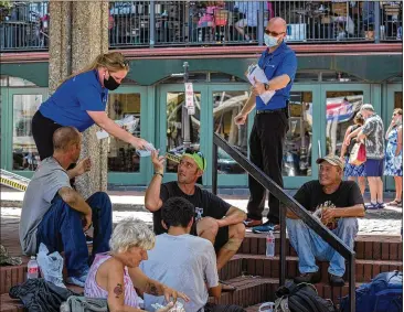  ?? PHOTOS BY STEPHEN B. MORTON / FOR THE AJC ?? Nicole Bush and Matthew Krueger, members of the COVID Resource Team, hand out masks to a group of people eating lunch outside in downtown Savannah.