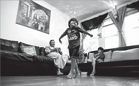  ?? CHRIS SWEDA/CHICAGO TRIBUNE ?? Osama Omarein, 5, dances in his family’s West Rogers Park apartment while his father and brother watch. The Syrian refugees came to the United States three years ago.