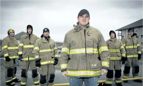  ?? THE CANADIAN PRESS FILES ?? Firefighte­r Mark Stephenson, centre, poses with fellow firefighte­rs in this file photo. For Stephenson, the Alberta oilsands capital is his home and, despite delays, he plans to rebuild on the same spot where his house went up in flames.